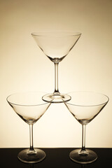 Three empty clean glasses on black table against beige background