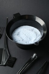 Bleaching powder and hairdresser's tools on black background, closeup