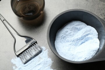 Bleaching powder and hairdresser's tools on grey table, closeup