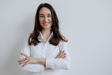 Young woman smiling confidently with arms crossed in front of a neutral background during a casual...