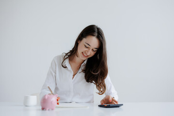 Young woman managing finances with calculator at a minimalistic desk in bright indoor setting