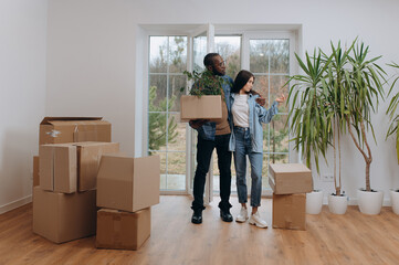 Couple Embracing in a Bright Room Surrounded by Moving Boxes and a Plant