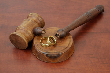 Wedding rings and broken judge gavel on table. 