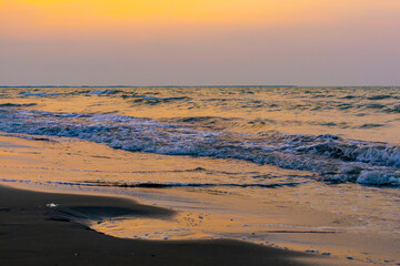 Exotic sunset paints the sky as waves kiss the shore. A serene blend of colors and motion, perfect for conveying tranquility and beauty.