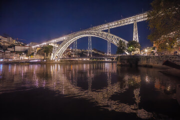 Porto, Portugal - A mesmerizing view of the Douro River at night with the Ponte Dom Luis I bridge brilliantly illuminated against the dark skyline.