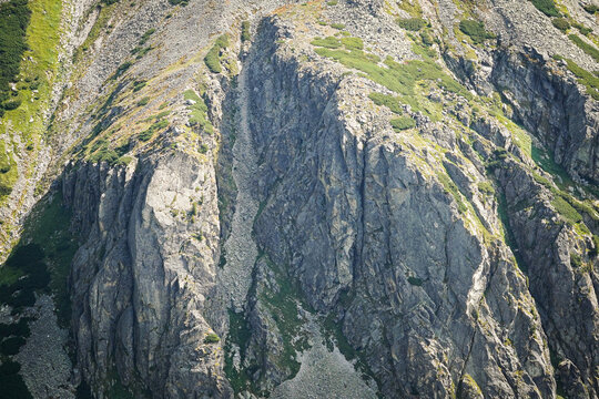 Close up to mountain side cliffs with green grass and sharp shadows and bright highlights, High Tatra mountains, Slovakia