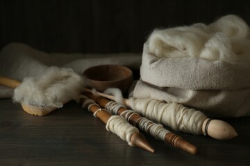 Soft white wool and spindles on wooden table, closeup