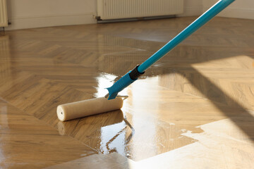 Polishing parquet with roller and varnish indoors, closeup