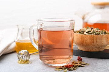 Delicious herbal tea with honey and dry leaves on grey table, closeup