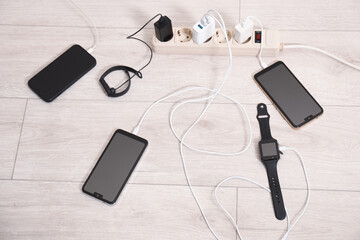 USB adapters with cables plugged into power strip charging devices on wooden floor, above view
