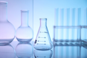 Laboratory glassware on mirror surface against color background