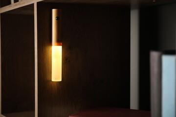 Glowing modern LED lamp on shelf indoors, closeup
