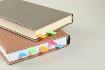 Books with colorful tabs on light gray background, closeup. Space for text