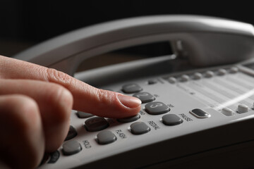 Woman dialing number on landline telephone, closeup