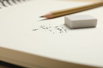 Eraser, pencil and scraps on notebook, closeup