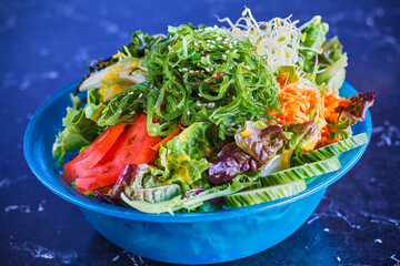 Asian style seaweed salad with tomato, cucumber, and shredded carrot topped with a sesame ginger...