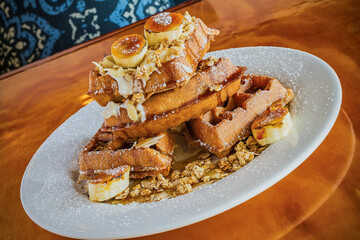 banana fosters waffles topped with granola, fresh banana, and caramel sauce