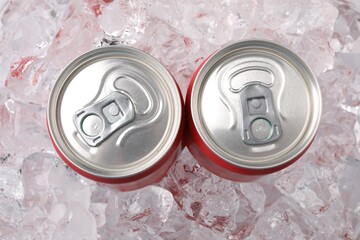 Refreshing drinks in cans on ice cubes, top view