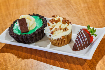dessert trio with pistachio custard, carrot cupcake, and chocolate dipped strawberry