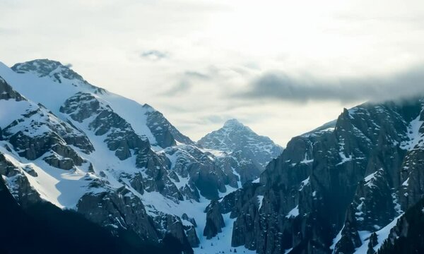 Scenic landscape with beautiful snow mountains in low clouds
