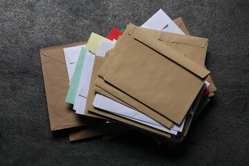 Stack of different paper envelopes on dark grey table, top view. Post office