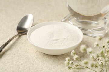 Collagen powder in bowl, spoon and gypsophila branches on light textured table, closeup