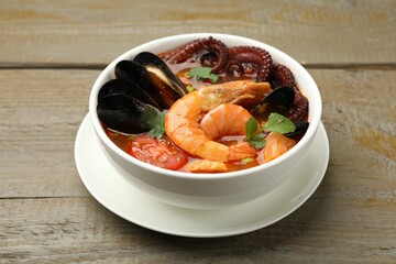 Delicious seafood soup in bowl on wooden table, closeup