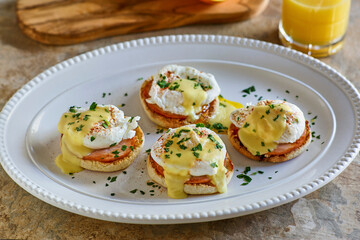 eggs benedict with Canadian bacon and hollandaise sauce topped with fresh herbs