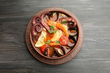 Tasty seafood soup in bowl on wooden table, top view