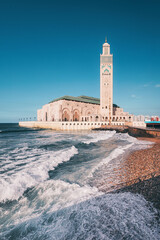 Ocean waves crashing against the Hassan II Mosque in Casablanca, Morocco, a stunning display of...