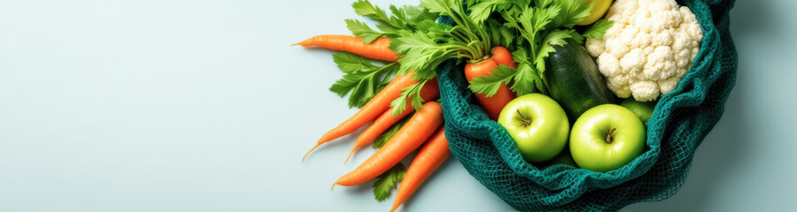 teal reusable bag filled with fresh carrots celery cauliflower zucchini and green apples