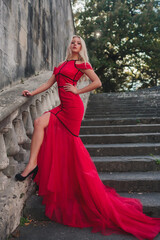 Fototapeta premium A Stunningly Elegant Woman Dressed in a Red Dress Against a Beautiful Scenic Cityscape
