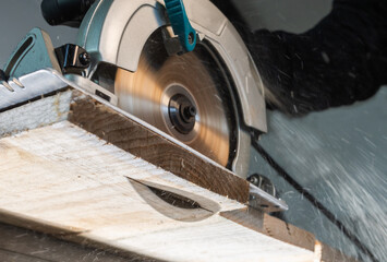 Close-up of a carpenter using a circular saw to cut  board