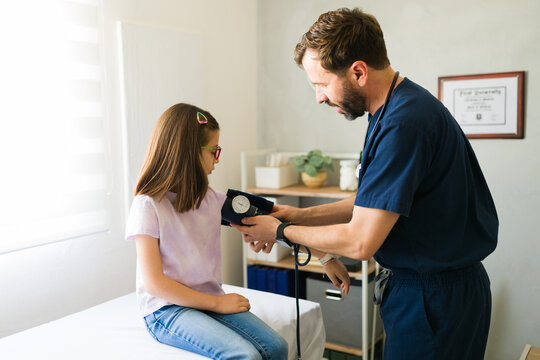 Pediatrician measuring blood pressure of female patient during routine medical checkup in clinical setting