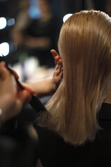 Fototapeta premium professional hairstylist carefully combs sleek blonde hair in a stylish salon. Precision haircut and beauty care in a modern setting