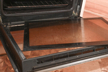 dirty glass with greasy spots was removed from the oven door to clean it.