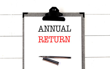 Clipboard with text annual return and pen on white wooden background in minimal business