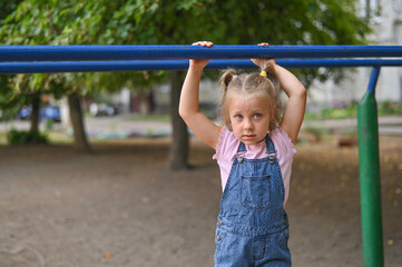 Fototapeta premium The girl is hanging on the crossbar