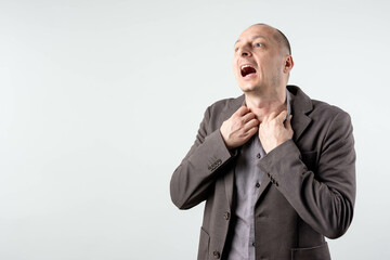 A bald, mature businessman struggling with a panic attack, choking in anxiety, isolated against a...