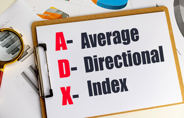 Clipboard with text average directional index abbreviation on financial documents with graphs