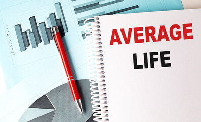 Notebook with text average life on white page with blue financial charts and red pen