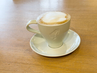 Foamy cappuccino on wooden table in bright café setting