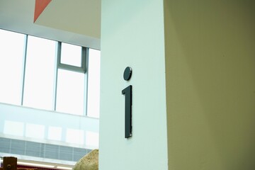 Minimalist black information sign mounted on a white wall inside a modern building. Clean architectural lines and natural light emphasize clarity and simplicity.