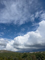 White cumulus clouds hang low over a mountain settlement