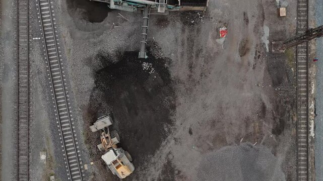 A drone captures an excavator with a bucket loading construction waste into a vibrator for sorting. Industrial worksite in action!