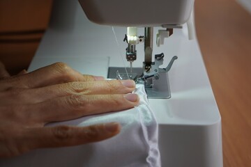 sewing, cutting and sewing. close up of a woman's hands sewing on a sewing machine.