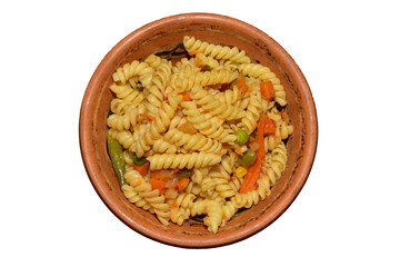 Fusilli pasta with vegetables in a clay plate, top view.