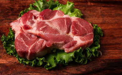 raw pork steak, two pieces, on a wooden background,