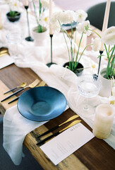 Black plate stands on a napkin next to the holiday menu on a set table