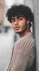 Young man with curly hair in casual oversized sweater, urban fashion lifestyle